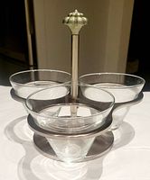 Front angled view of the chrome stand with three round glass bowls inserted, showing the arrangement and design of the set.