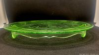 Side profile showing footed base and general shape of green glass plate