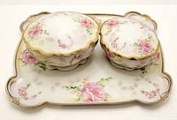 Front view of the dresser tray holding two lidded jars, displaying floral patterns with pink roses and gold rim accents.