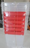 Stack of six small clear plastic storage bins with red front handles, factory sealed bundled with string