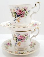 Two demitasse cups stacked on two matching saucers showing floral pattern detail and gold rims.