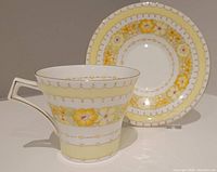 Cup and saucer set in Bohemia pattern with yellow floral band and gold trim on white background