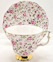 Tea cup and saucer set showing floral pattern with pink roses and gold trim.