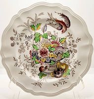 Front view of plate showing scalloped edges and central urn floral and bird design in color with brown foliage details.