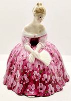 Front view of the Royal Doulton figurine Victoria showing the detailed pink floral dress and white fan.