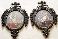 Front view of two vintage oval brass frames with one containing a portrait print of two women and the other a floral painting.