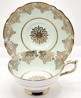 Teacup inside the matching saucer showing gold detailing and mint green color