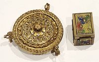 Two vintage trinket boxes, one round brass with filigree work and one smaller rectangular brass with colorful enamel butterfly motifs.