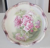 Top view of decorative porcelain bowl showing hand painted pink roses and scalloped edge with golden trim