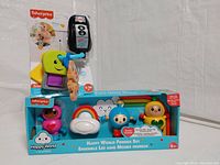 Two Fisher-Price baby toys: a Happy World Friends Set with three character figures and a cloud, along with a yellow elephant-shaped baby keys toy in original packaging