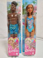 Male and female Barbie dolls in original packaging, showing front view with swimsuits and packaging graphics.