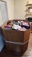 Large cardboard bin labeled 'Toys!' filled with assorted new toy packages