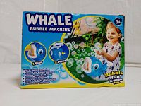 Photo of the front of the box showing the whale bubble machine image, instructions, and a child playing with bubbles.