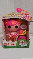 Front view of the Lalaloopsy Littles doll in original packaging showing doll with pink hair, pink outfit, and yellow snail accessory on a pink block.