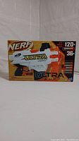 Nerf Ultra Amp blaster in white and orange, showing front of the box with product and features
