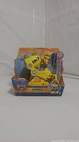 Front view of new in box Paw Patrol Rubble deluxe vehicle toy packaging showing vehicle and Rubble character figure inside.