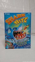 Front view of Shark Bite game box showing colorful shark illustration and game details.
