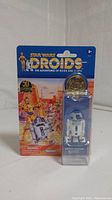 Front view of Star Wars Droids R2-D2 action figure in packaging with collector coin