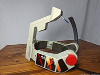 Three-quarter view showing the Konami Laser Scope headset on a wooden table, highlighting the side controls and padded ear cushions.