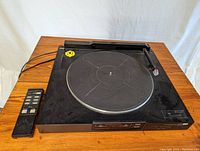 Top view of Sansui P-L45 record player with attached tonearm and remote control beside it, showing overall condition and details.