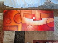 Full view of the three panel abstract oil painting in warm tones of red, orange, and yellow with geometric shapes.
