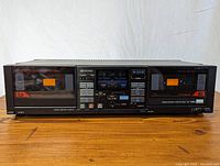 Front view of Sansui dual cassette deck showing centrally located buttons and display with two cassette compartments on left and right sides