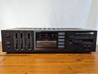 Front view of Sansui Model A-1100 receiver amplifier showing the full unit with bass, treble, balance sliders, analog tuner, function buttons, and power switch.