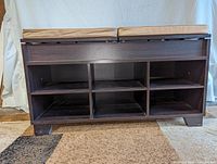 Front view of dark espresso shoe storage bench showing six open cubby holes for shoes and two seat cushions on top.