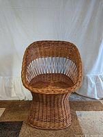 Front view of the wicker chair showing the rounded seat and curved backrest.