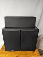 Front view showing one center channel speaker and two side speakers with black fabric covers and Yamaha logos.