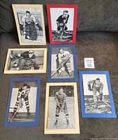 All seven vintage black and white hockey photos with colored backing paper, arranged on a couch for lot overview.