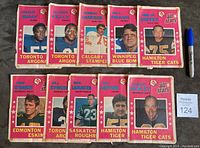 Full view of the near set of 10 1971 O.P.C. CFL All Stars poster inserts laid out with a pen for scale. Shows a selection of players from various teams including Toronto Argonauts, Calgary Stampeders, Winnipeg Blue Bombers, Hamilton Tiger Cats, Edmonton Eskimos and Saskatchewan Roughriders.