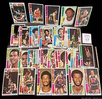 Full lot display of 37 Topps 1976-77 oversized basketball cards including Kareem Abdul-Jabbar, John Havlicek, Julius Erving, Bill Bradley, Walt Frazier and others shown face up on black surface.