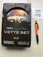 Closed cardboard wax box with white Corvette image on front, black background with rainbow design lines and product title text.