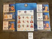 Full view of six sealed NHL stamp cards arranged around a central 50th All-Star Game commemorative sheet, each sealed in protective plastic.