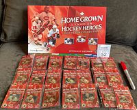 Red album cover with images of hockey players and a red display stand behind 22 sealed pin packages arranged in front.