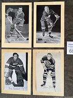 Four black-and-white Group 2 Beehive hockey photos showing John MacMillan, Bob Nevin, Terry Sawchuck, and Adam Brown in original backing paper. Players posed with hockey sticks and gear.