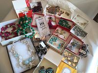 Full lot overview showing multiple costume jewelry pieces including boxed earrings and necklaces in various colors and materials.