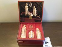 Boxed set of four pieces including three porcelain figures and one crystal star suspended above, displayed on a wooden surface.