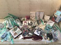 Wide shot of entire jewelry lot on surface showing mix of bracelets, necklaces, small boxes and zip baggies