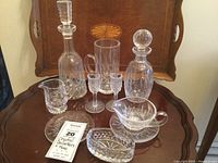 Overall lot view on a wooden table with a brown tray behind, displays all crystal items in the lot for identification