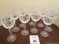 Nine crystal wine glasses arranged on wooden surface showing front view