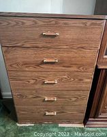 Full frontal view of the chest showing the five wooden drawers with brass handles and wood grain finish.