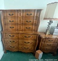 Full view of classic wood chest of drawers with six drawers and brass handles, showing the curved front and carved accents.