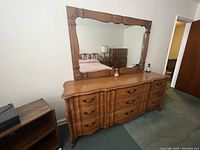 Classic wood 9 drawer dresser with attached large mirror, showing carved wood details and curved drawer fronts.