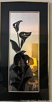 Framed glass mirror wall decor with black flower etched design, black border, and gold trim visible from front angle.