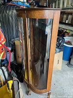 Side angled photo showing curved vintage glass panels and wood trim of the curio cabinet