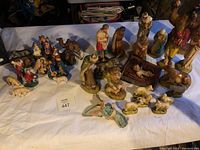 Photo showing larger ceramic nativity figurines including Mary, Joseph, Baby Jesus, three wise men, shepherds, camels, and lambs arranged on table