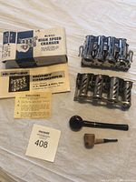 Two vintage metal money changers on the right, one clean with original box and instructions on the left. Two vintage pipes placed in front.