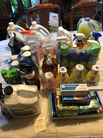 Wide view of entire lot showing assorted cleaning products including laundry detergent, fabric softener, dish soap, disinfectant spray, and cleaning cloths.